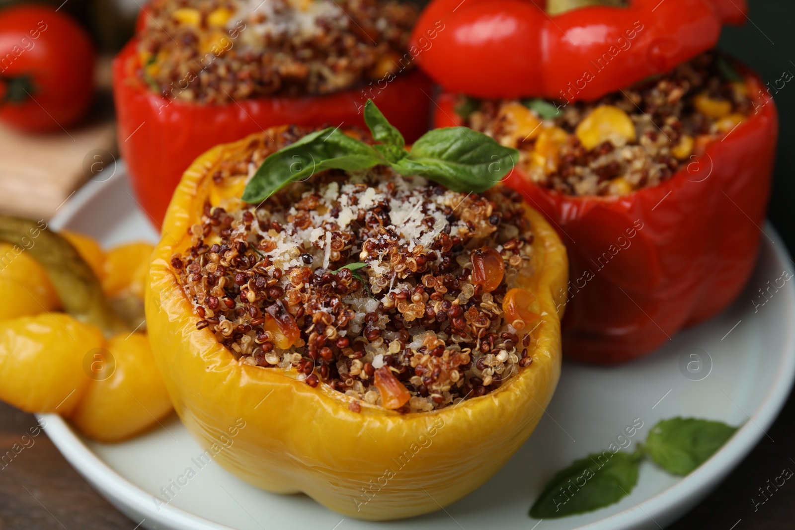 Photo of Quinoa stuffed peppers with corn and basil on wooden table, closeup