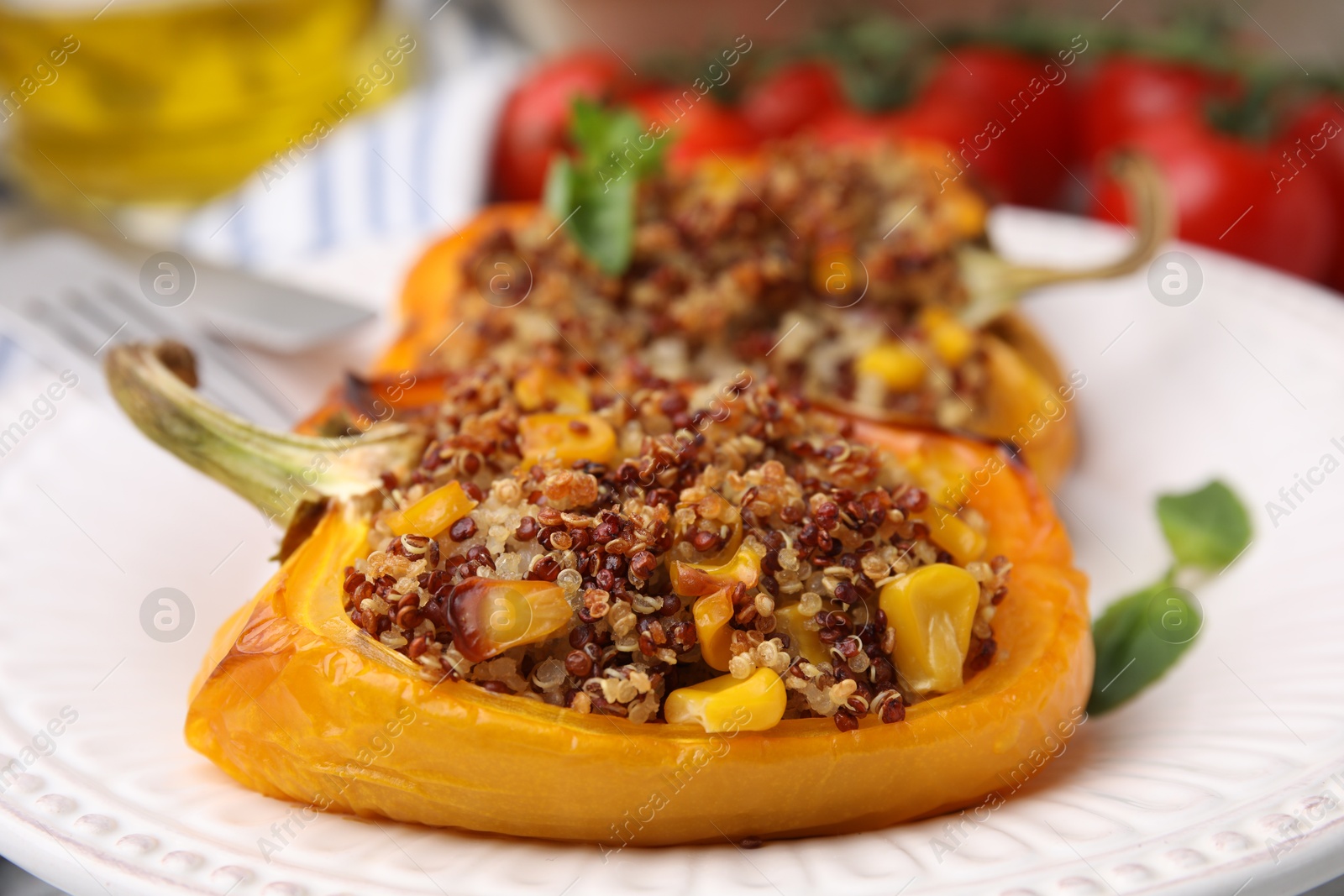 Photo of Quinoa stuffed peppers with corn and basil on table, closeup