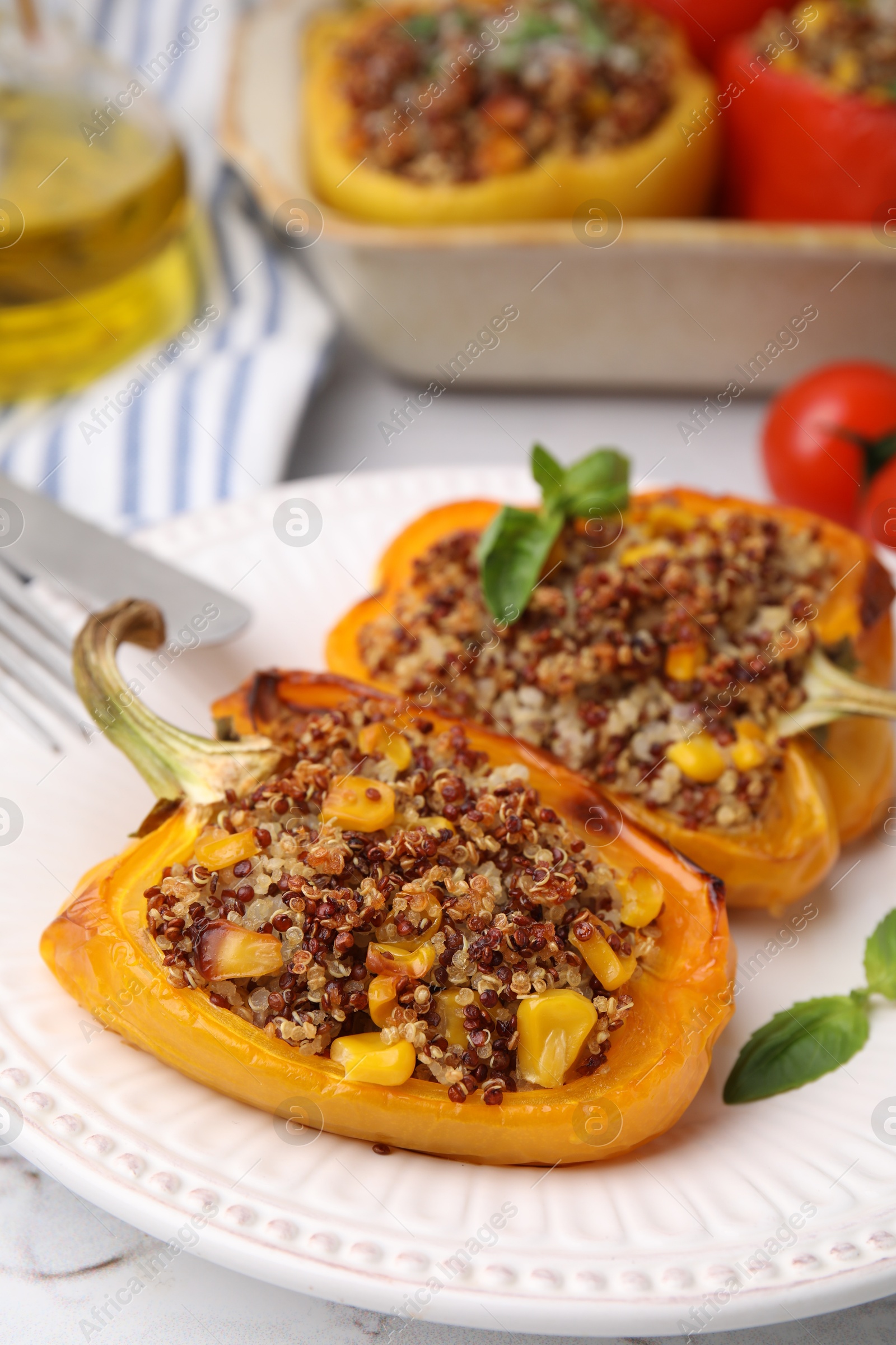 Photo of Quinoa stuffed peppers with corn and basil on white textured table, closeup