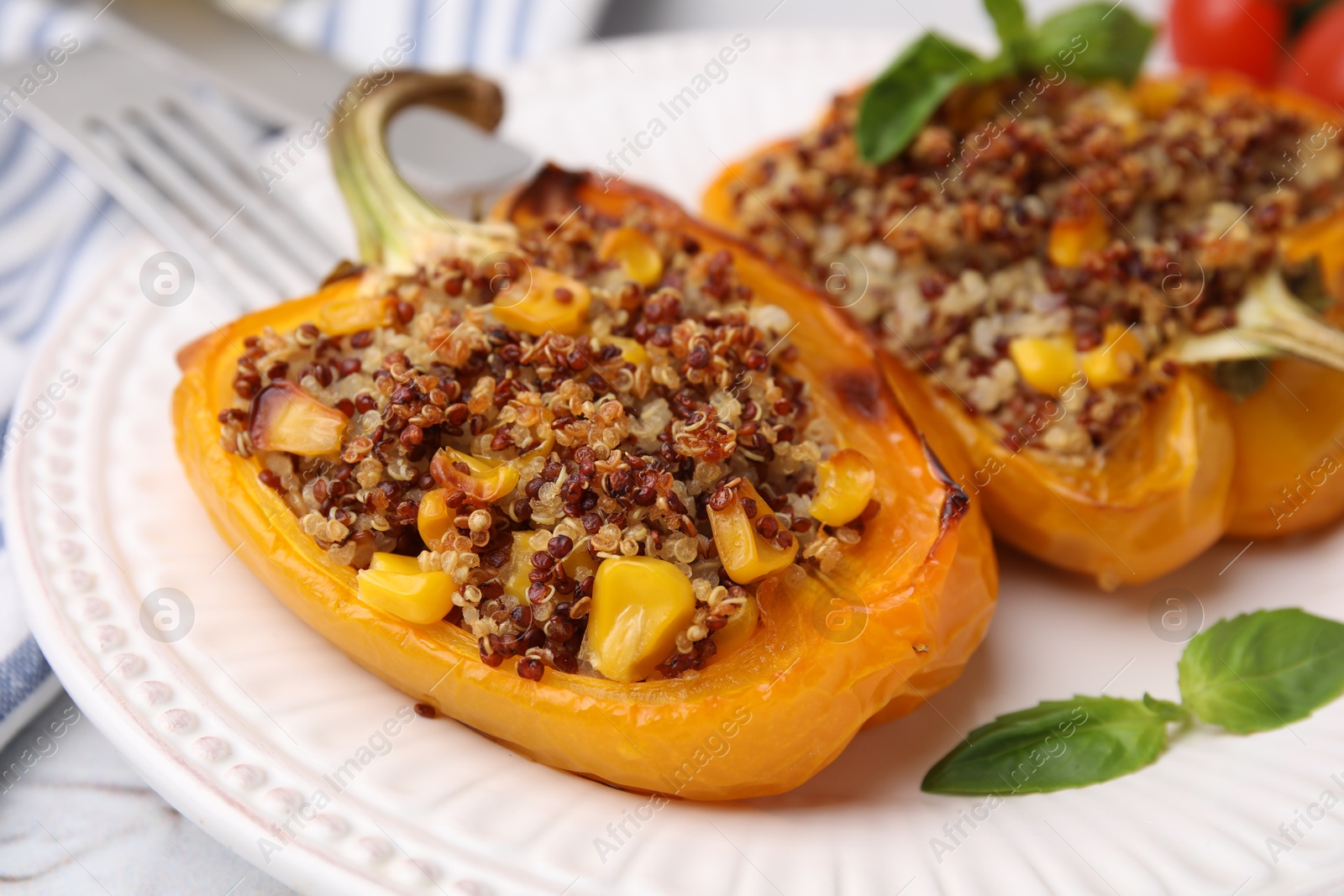 Photo of Quinoa stuffed peppers with corn and basil on white textured table, closeup