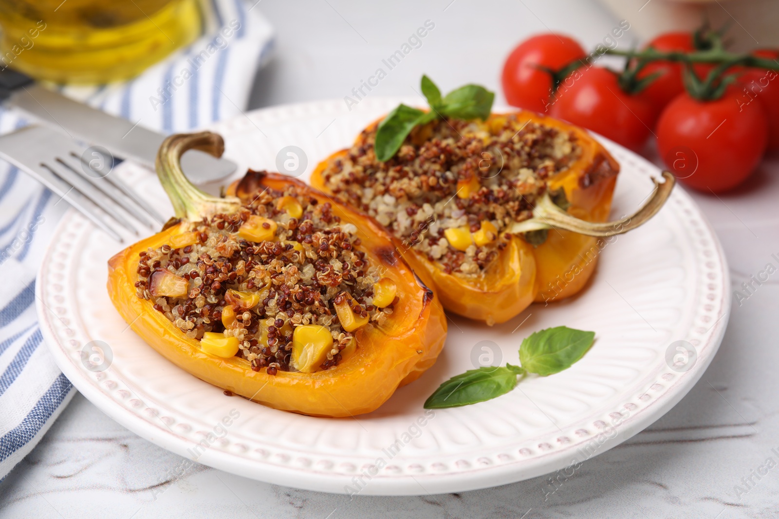 Photo of Quinoa stuffed peppers with corn and basil on white textured table