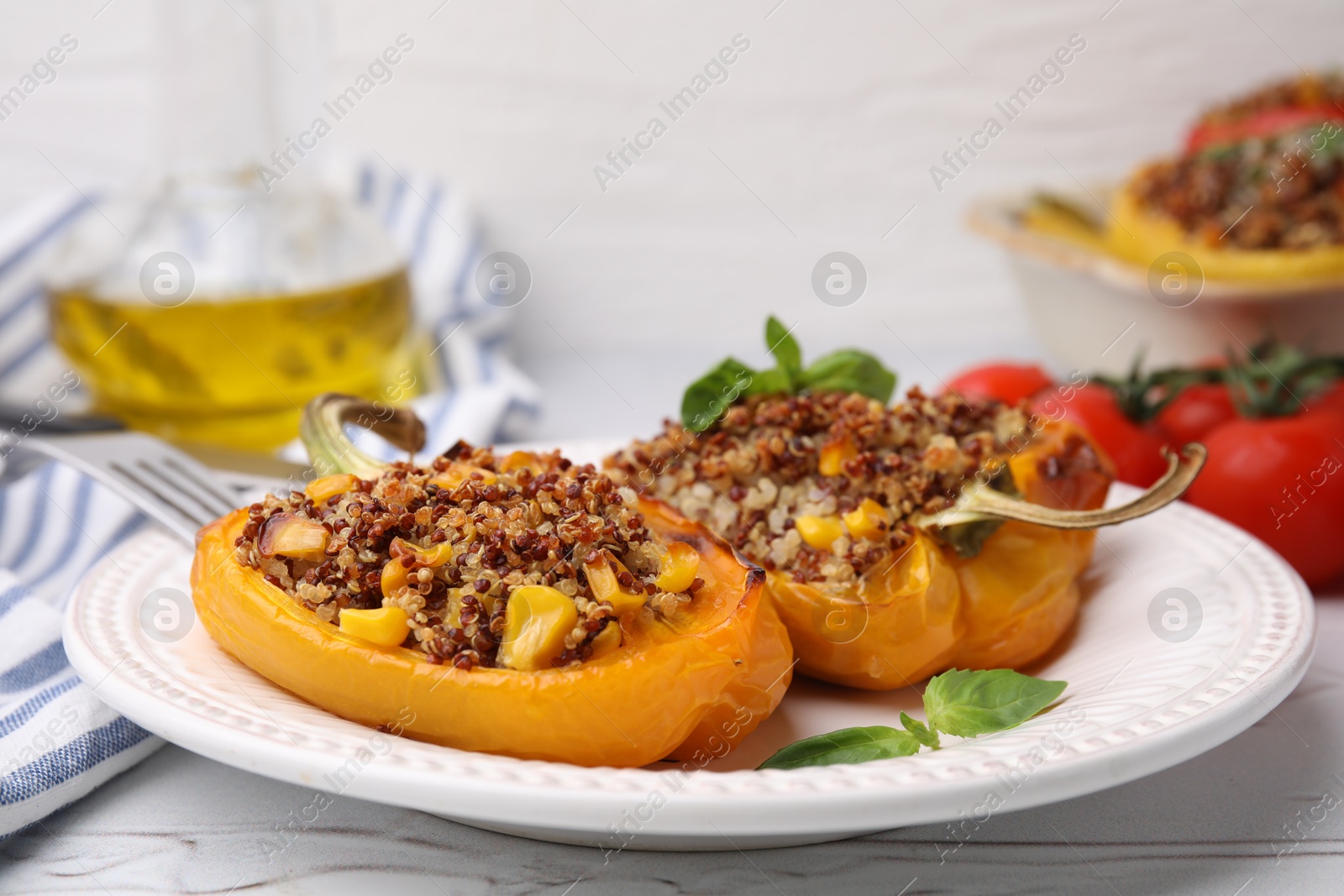 Photo of Quinoa stuffed peppers with corn and basil on white textured table