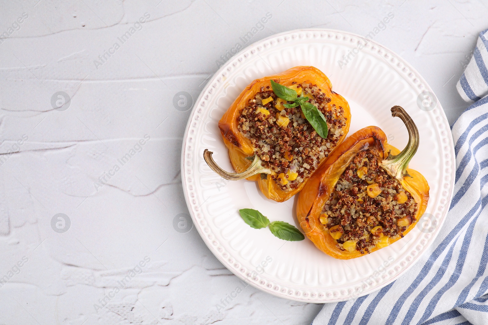 Photo of Quinoa stuffed peppers with corn and basil on white textured table, top view. Space for text