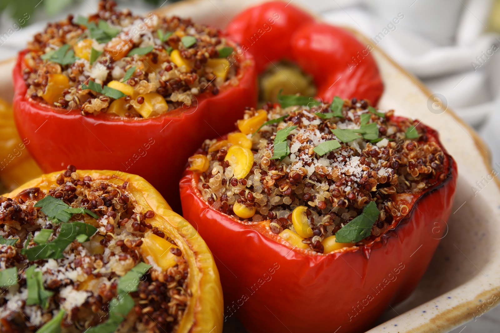 Photo of Tasty quinoa stuffed bell peppers with corn in baking dish on table, closeup