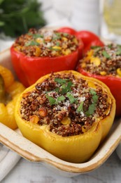 Photo of Tasty quinoa stuffed bell peppers with corn in baking dish on table, closeup