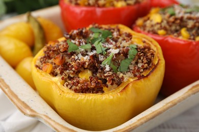 Photo of Tasty quinoa stuffed bell peppers with corn in baking dish on table, closeup