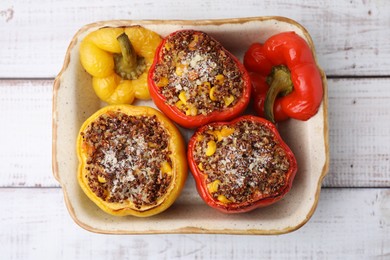 Photo of Tasty quinoa stuffed bell peppers with corn in baking dish on white wooden table, top view