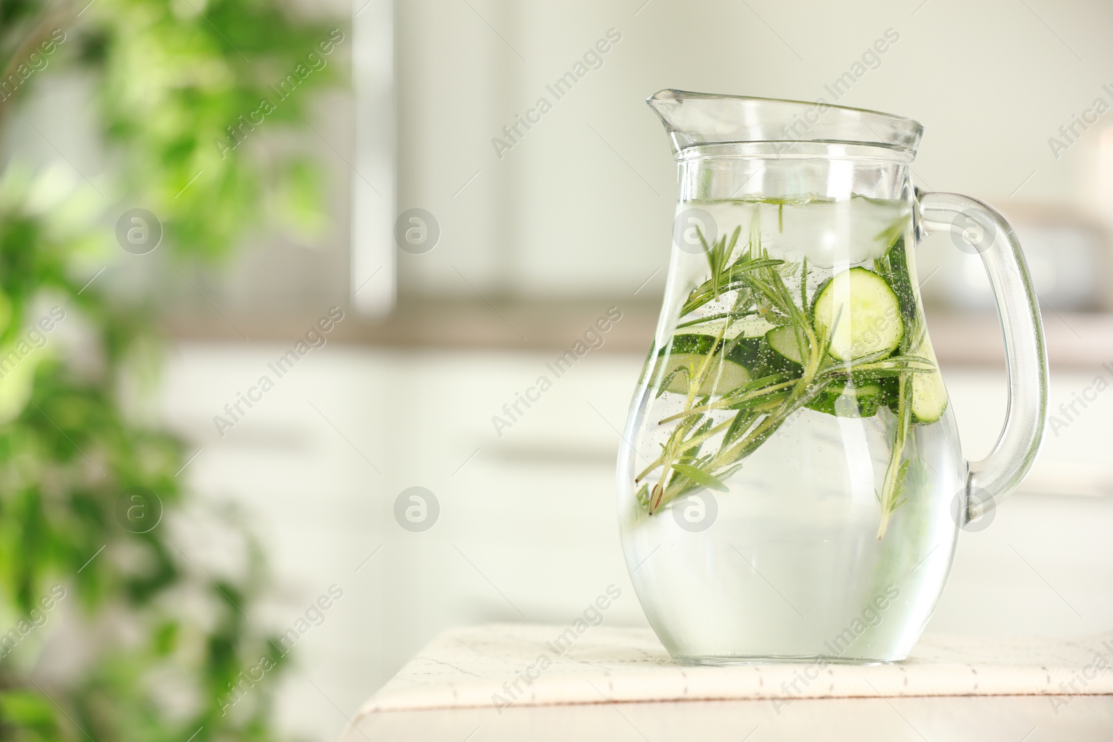 Photo of Refreshing cucumber water with rosemary in jug on white table, closeup. Space for text