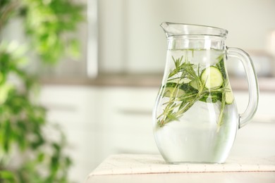 Photo of Refreshing cucumber water with rosemary in jug on white table, closeup. Space for text