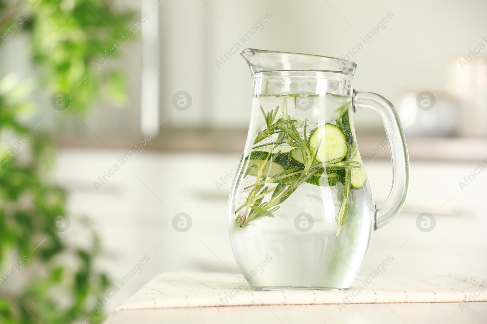 Photo of Refreshing cucumber water with rosemary in jug on white table, closeup. Space for text