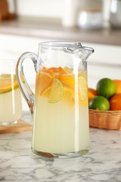 Photo of Refreshing lemonade with orange and lime in jug on white marble table