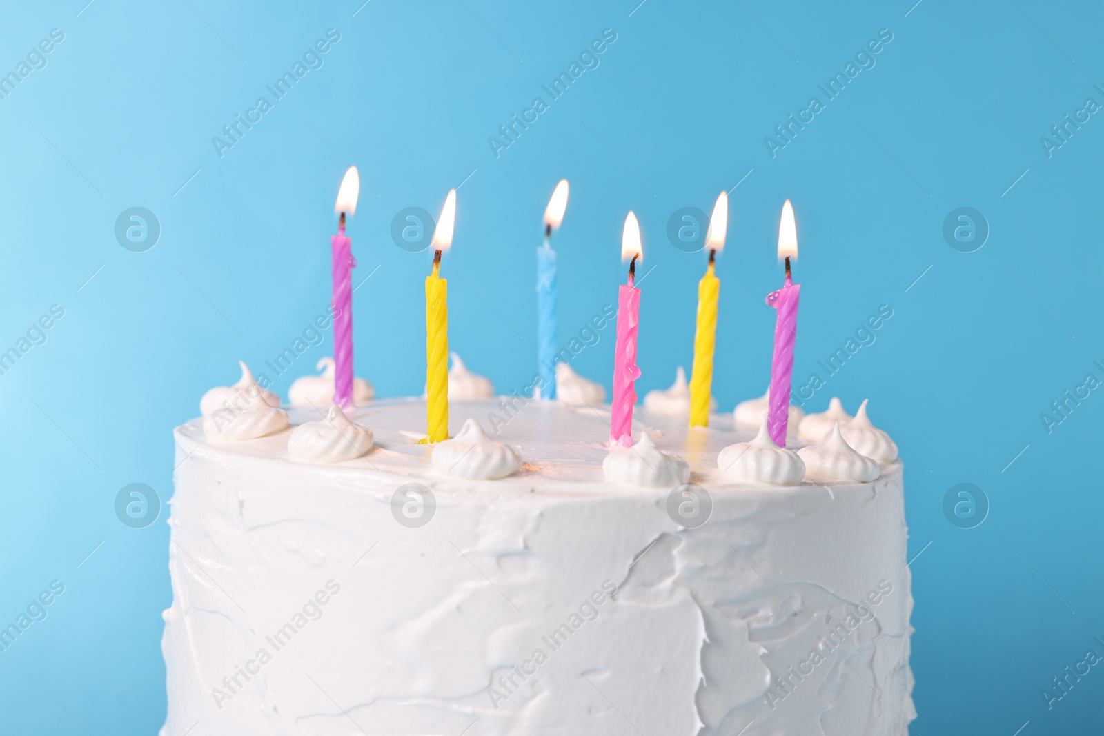 Photo of Tasty Birthday cake with burning candles against light blue background, closeup