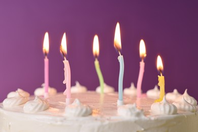 Tasty Birthday cake with burning candles against purple background, closeup