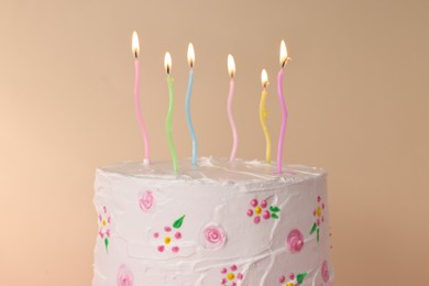 Photo of Tasty Birthday cake with burning candles against beige background, closeup