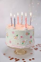 Photo of Tasty Birthday cake with burning candles and confetti on white table