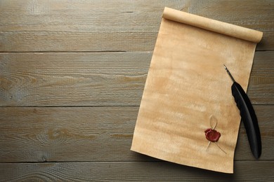 Sheet of old parchment paper with wax stamp and black feather on wooden table, top view. Space for text