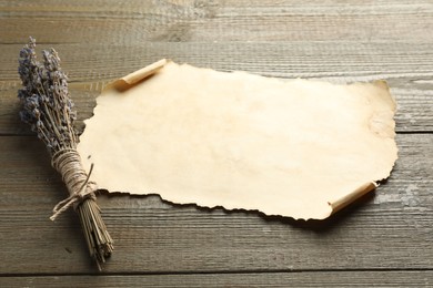 Photo of Sheet of old parchment paper and lavender flowers on wooden table