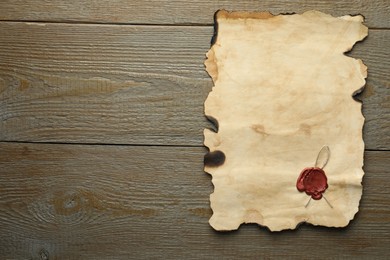 Photo of Sheet of old parchment paper with wax stamp on wooden table, top view. Space for text