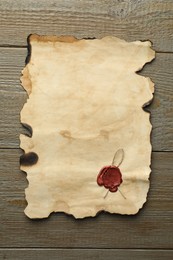 Photo of Sheet of old parchment paper with wax stamp on wooden table, top view