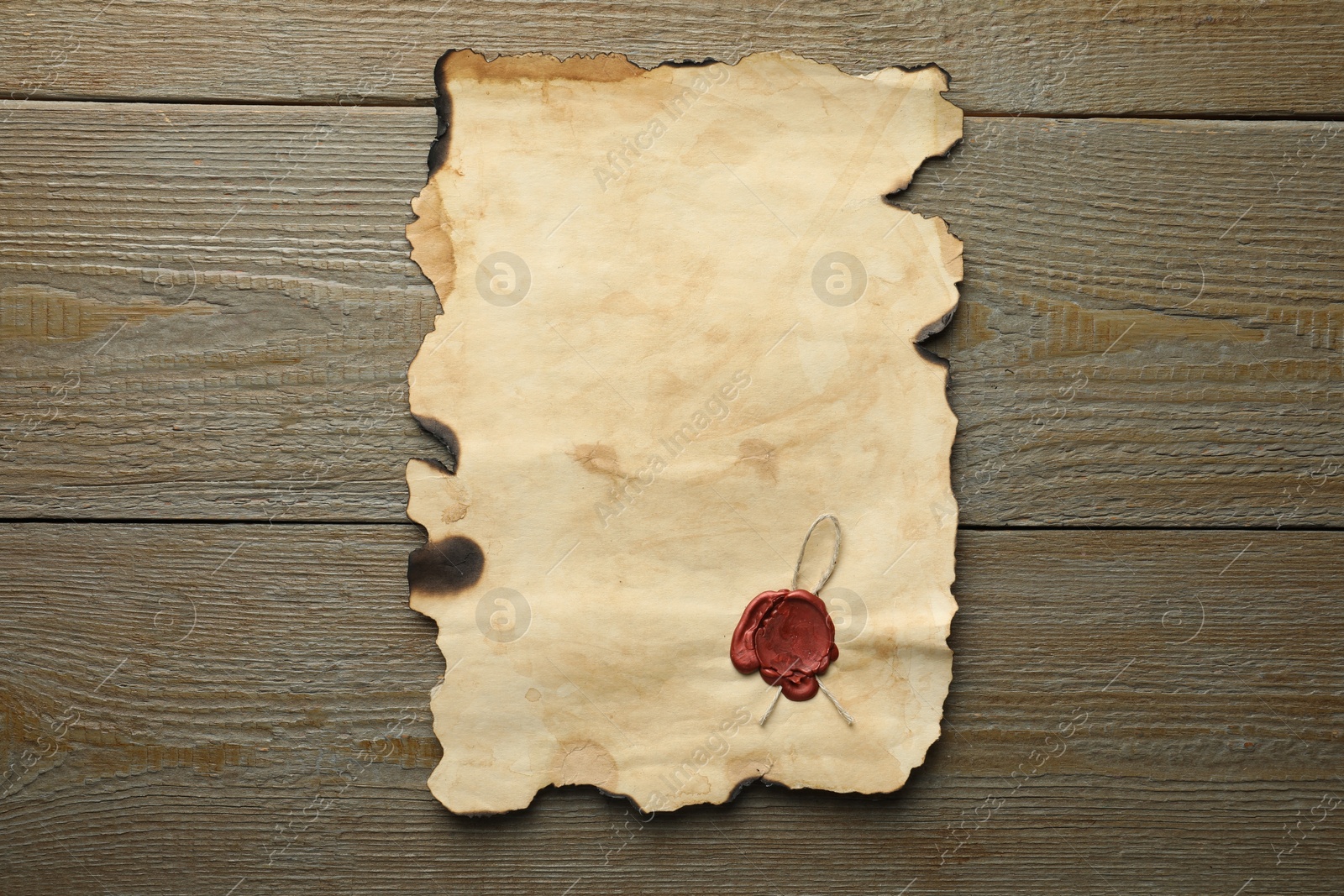 Photo of Sheet of old parchment paper with wax stamp on wooden table, top view