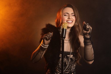 Beautiful young woman with microphone singing in color lights and smoke