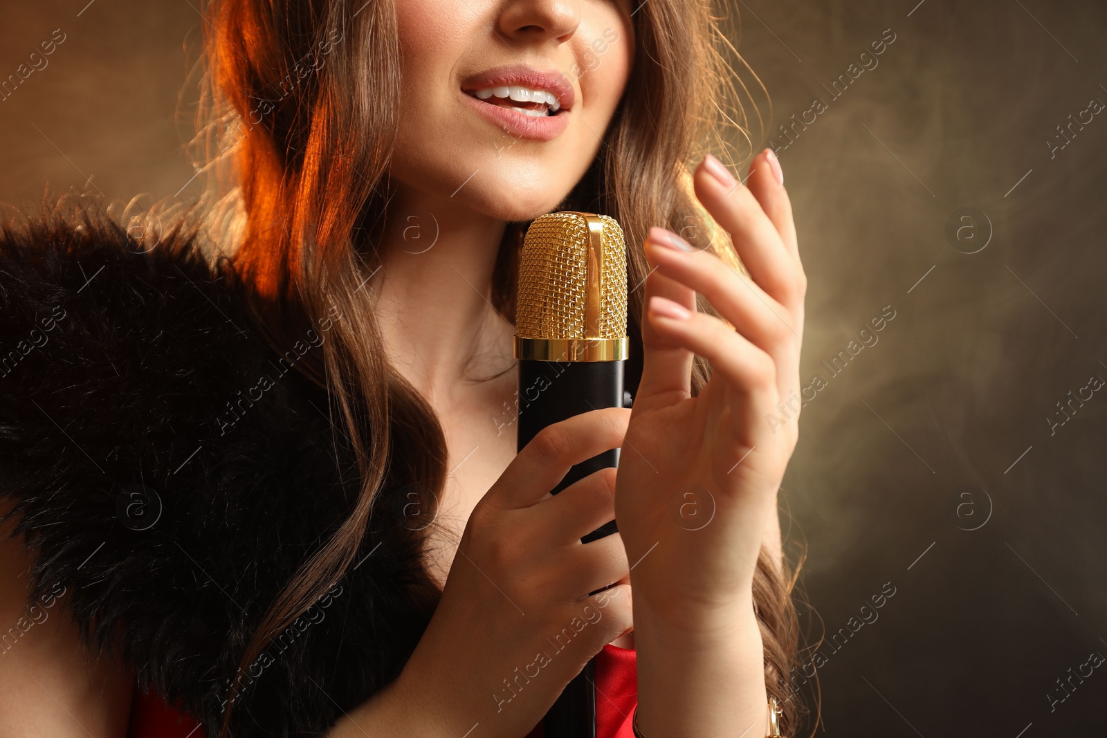 Photo of Woman with microphone singing on color background with smoke, closeup