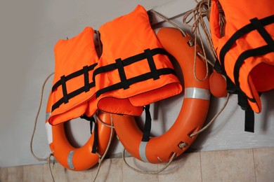 Orange lifebuoys and life vests hanging on wall at station
