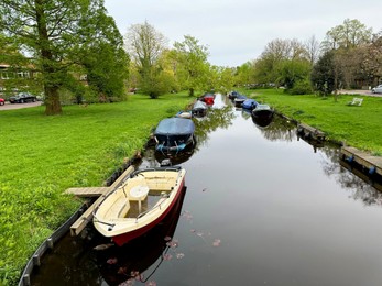 Canal with moored boats near green shore