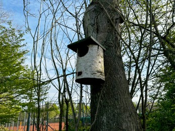 Beautiful wooden birdhouse hanging on tree trunk in park