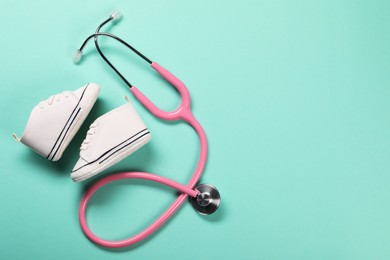 Photo of Stethoscope and kid's sneakers on turquoise background, flat lay. Space for text