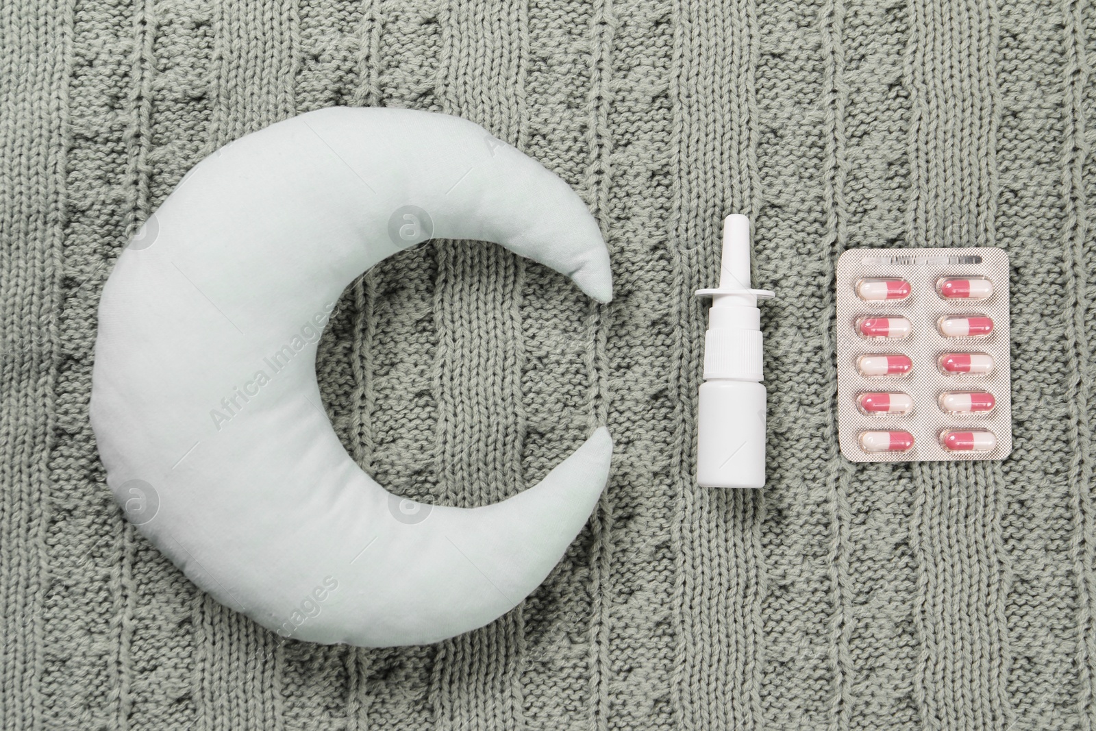 Photo of Pillow, pills and nasal spray on blanket, flat lay