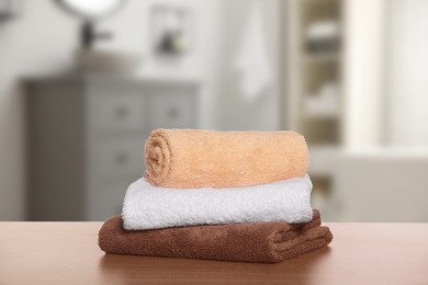 Image of Stack of fresh towels on wooden against blurred bathroom interior