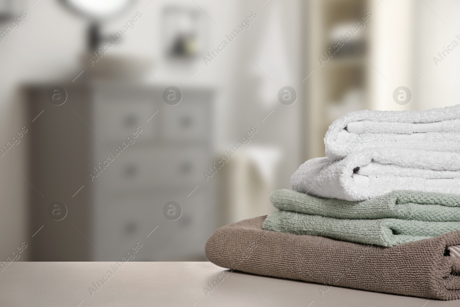 Image of Folded fresh towels on table in bathroom. Space for text