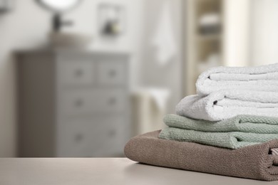 Image of Folded fresh towels on table in bathroom. Space for text