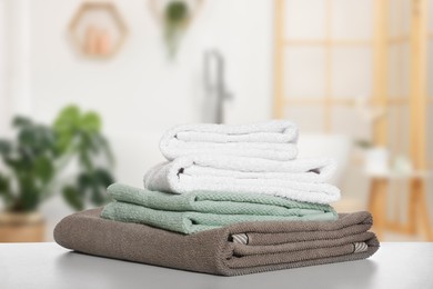 Image of Folded fresh towels on table against blurred bathroom interior