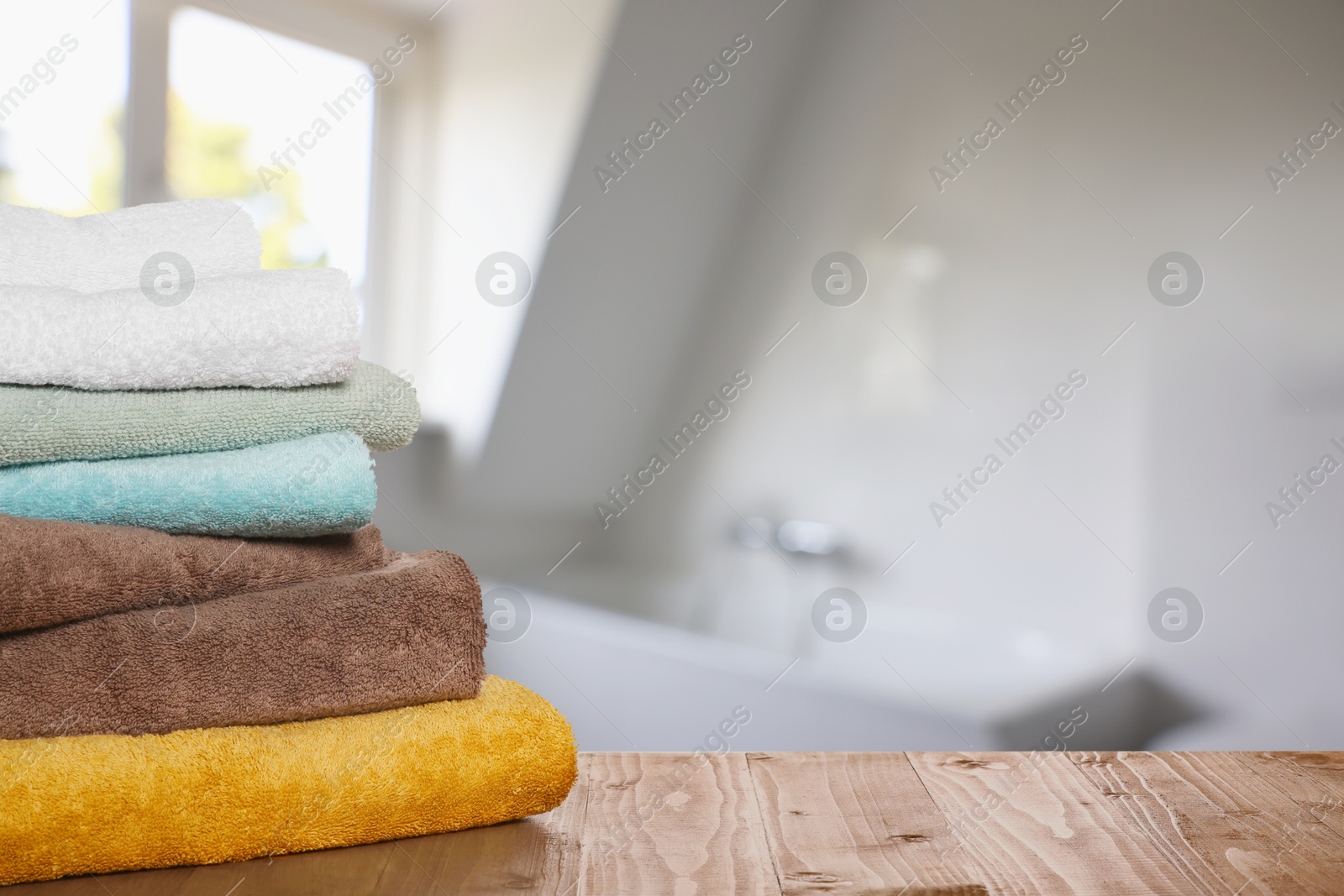 Image of Folded fresh towels on wooden table in bathroom. Space for text