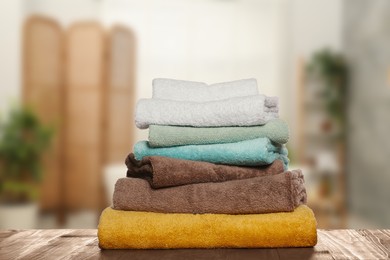 Image of Folded fresh towels on wooden against blurred bathroom interior