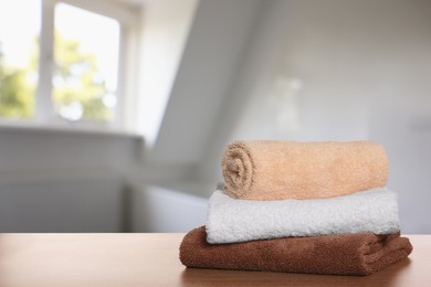 Stack of fresh towels on wooden table in bathroom. Space for text