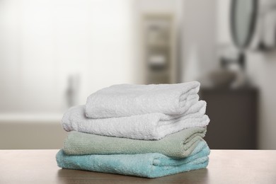 Folded fresh towels on wooden against blurred bathroom interior