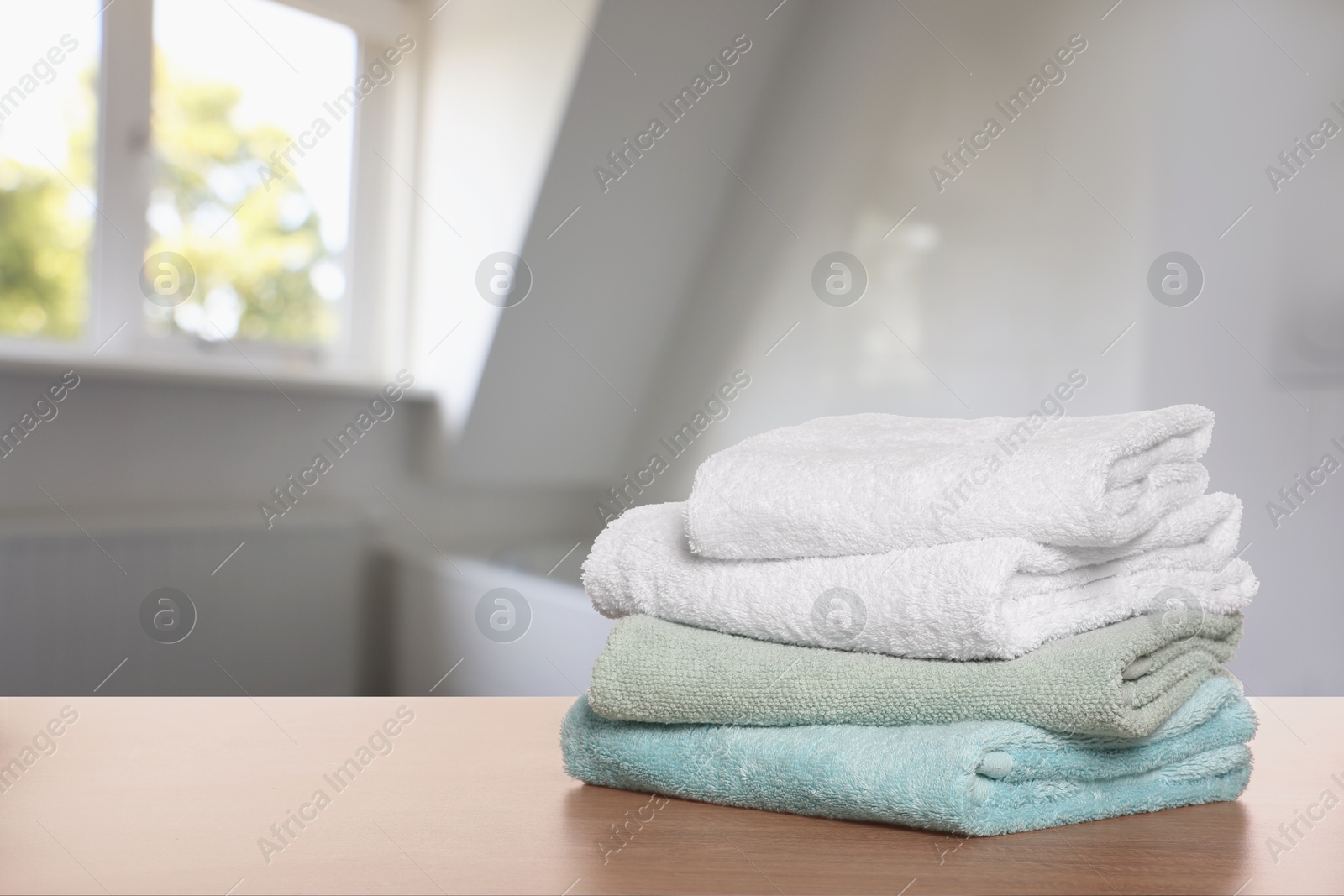 Image of Folded fresh towels on wooden table in bathroom. Space for text