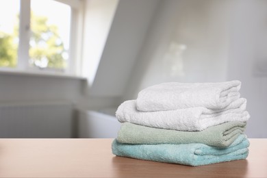 Image of Folded fresh towels on wooden table in bathroom. Space for text