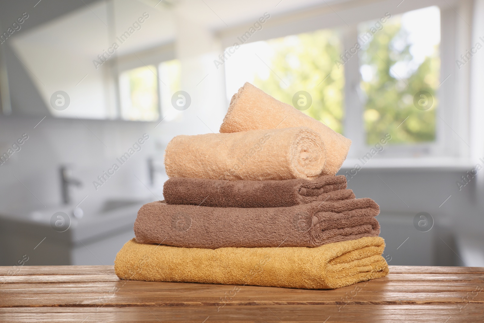 Image of Stack of fresh towels on table against blurred bathroom interior