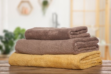 Folded fresh towels on wooden against blurred bathroom interior