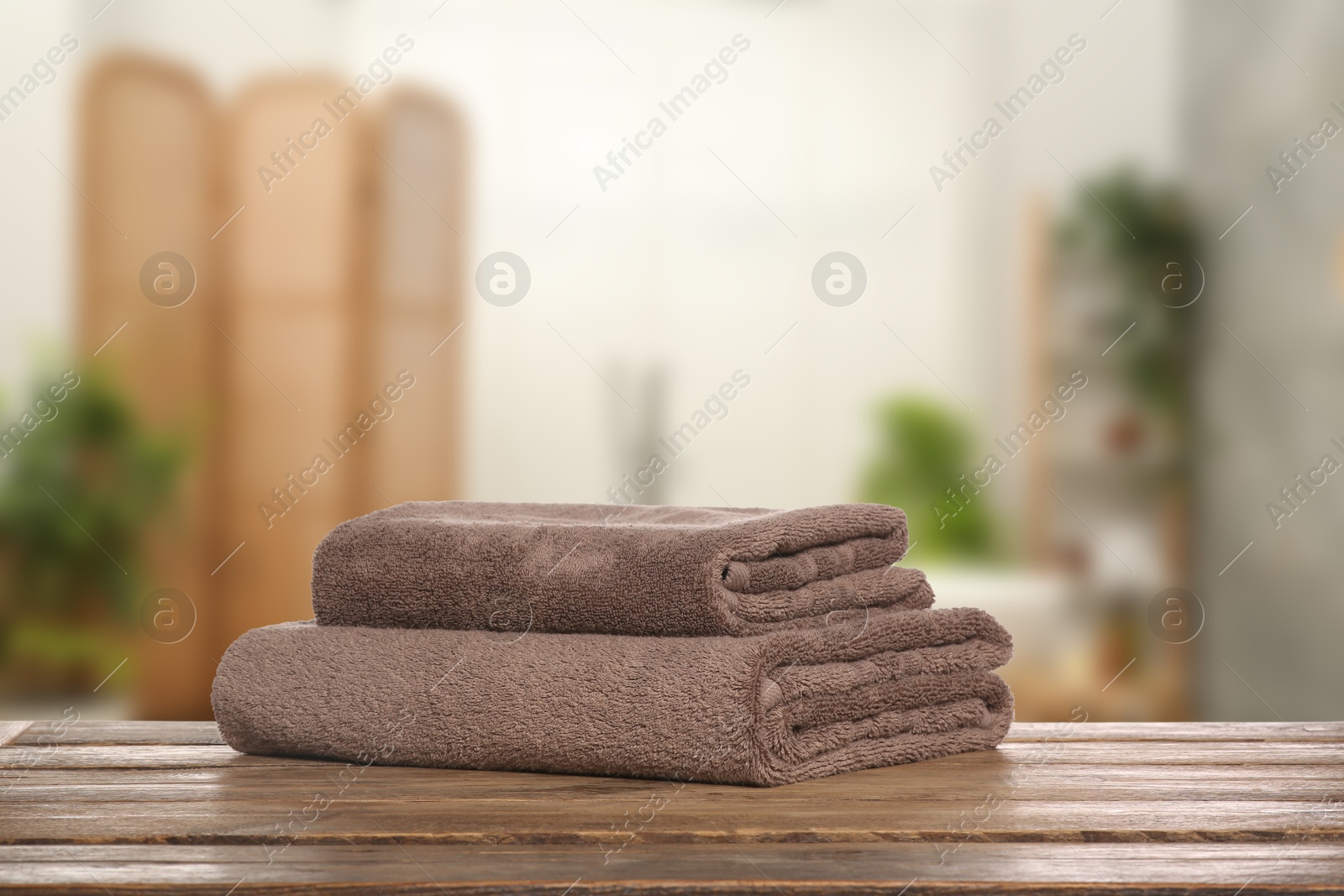 Image of Folded fresh towels on wooden table in bathroom. Space for text