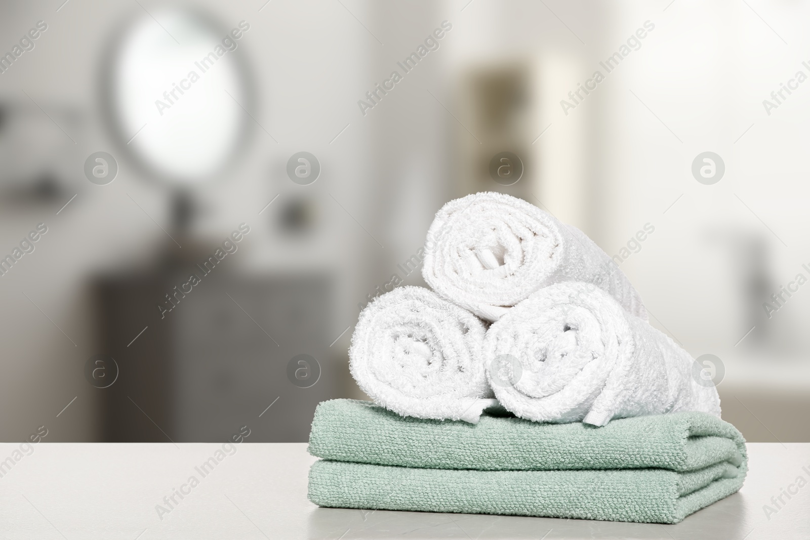 Image of Stack of fresh towels on table in bathroom. Space for text