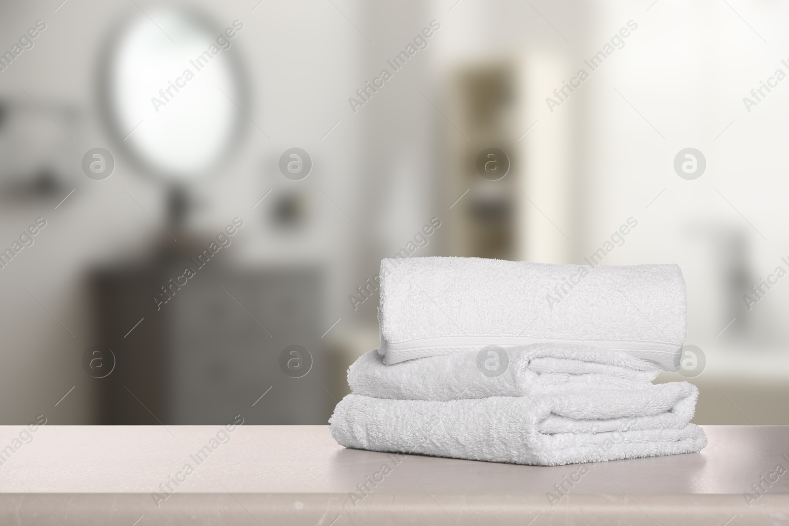 Image of Folded fresh towels on table in bathroom. Space for text