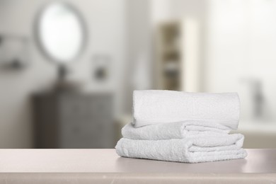 Image of Folded fresh towels on table in bathroom. Space for text