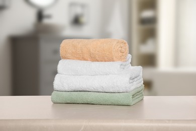 Image of Folded fresh towels on table against blurred bathroom interior