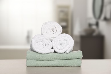 Stack of fresh towels on table against blurred bathroom interior