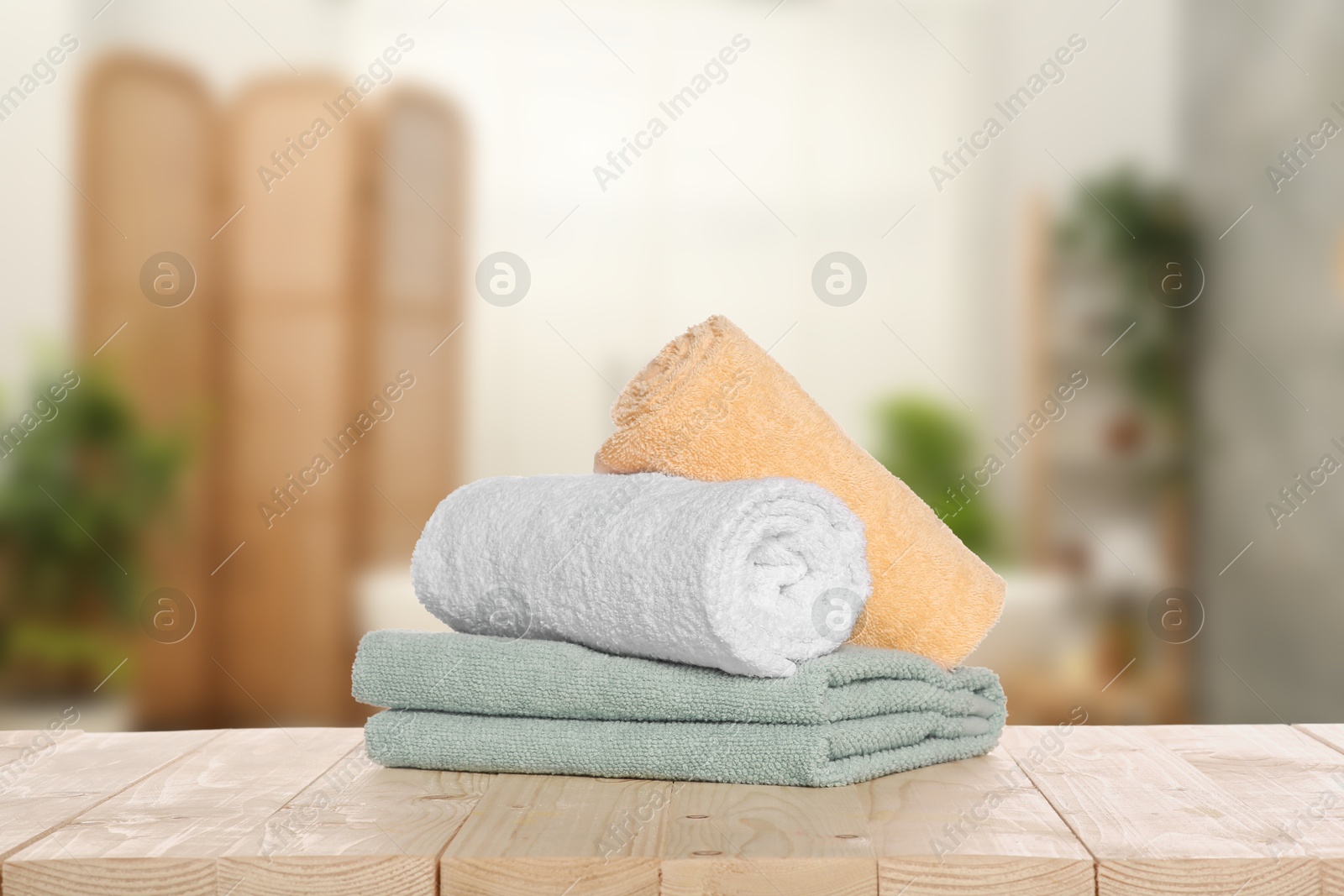 Image of Stack of fresh towels on table against blurred bathroom interior